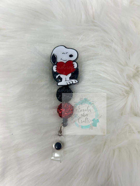 Dog holding heart badge reel